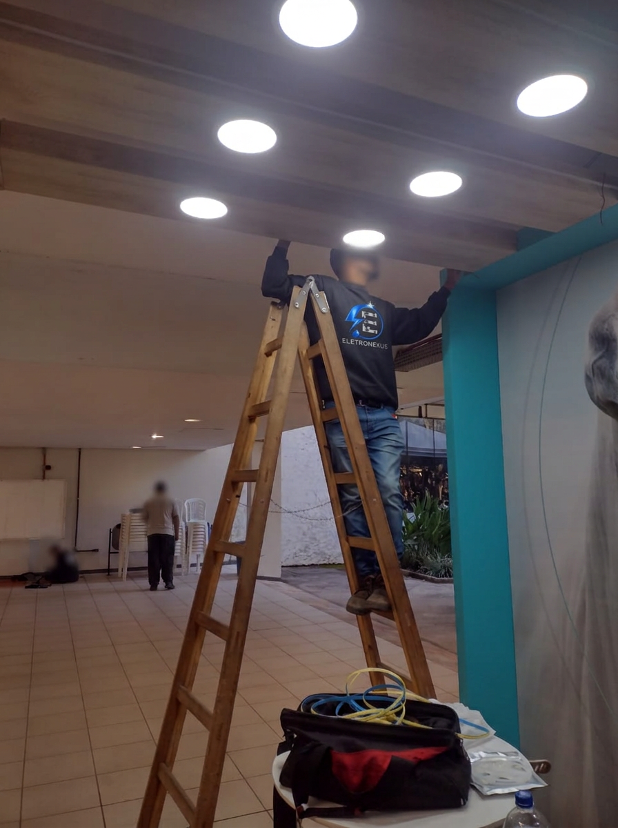 Eletricista da ELETRONEXUS instalando luminárias no teto